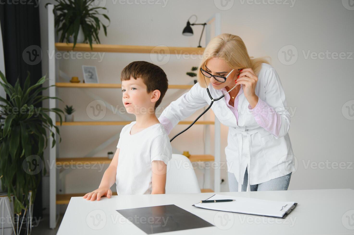 Pediatrician doctor examining little boy's heart beat and lungs to check for problems photo