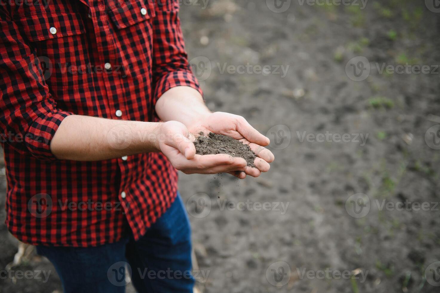 A farmer in boots works with his tablet in a field sown in spring. An agronomist walks the earth, assessing a plowed field in autumn. Agriculture. Smart farming technologies photo