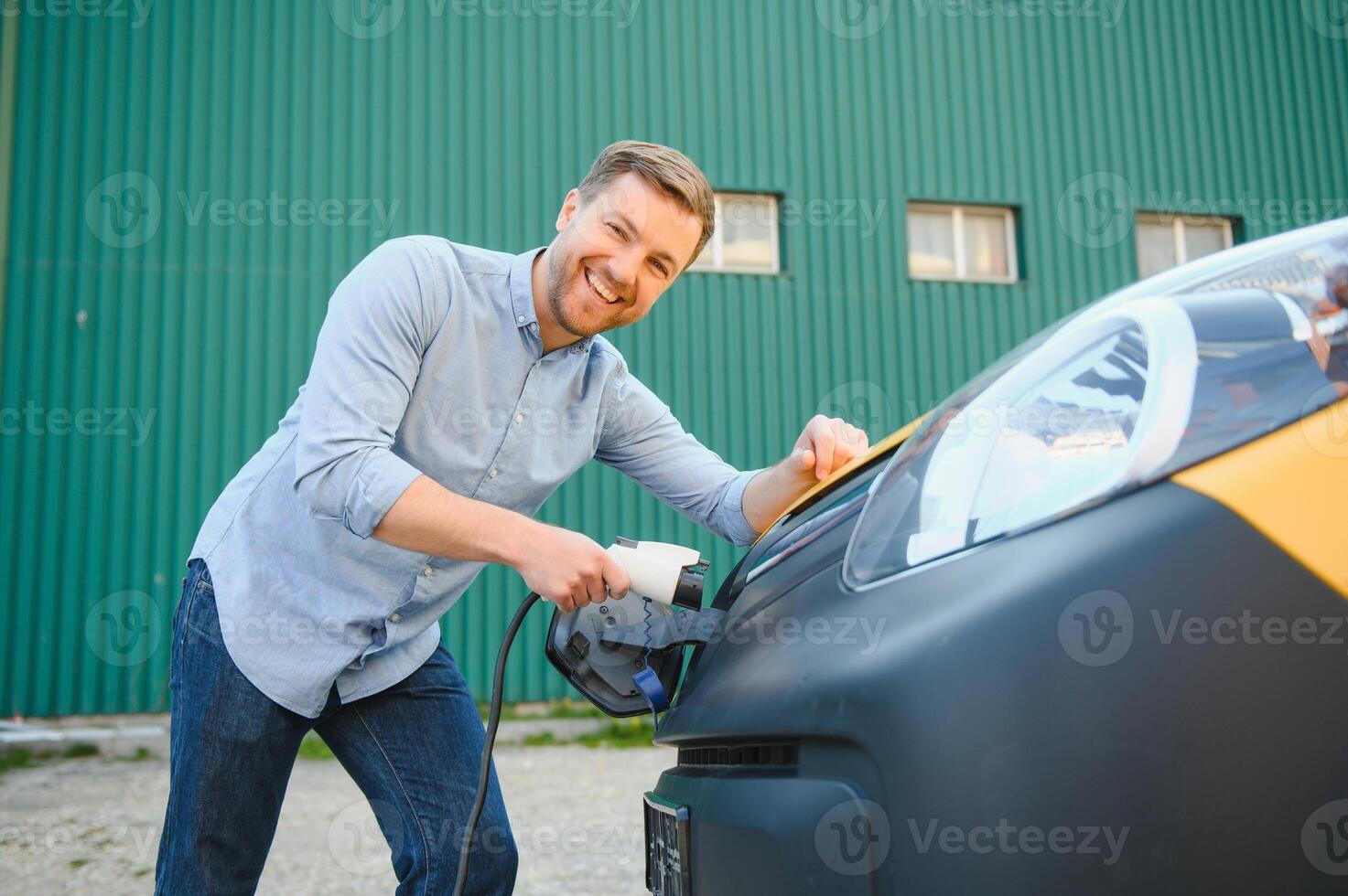 Man charging electric car by the house photo