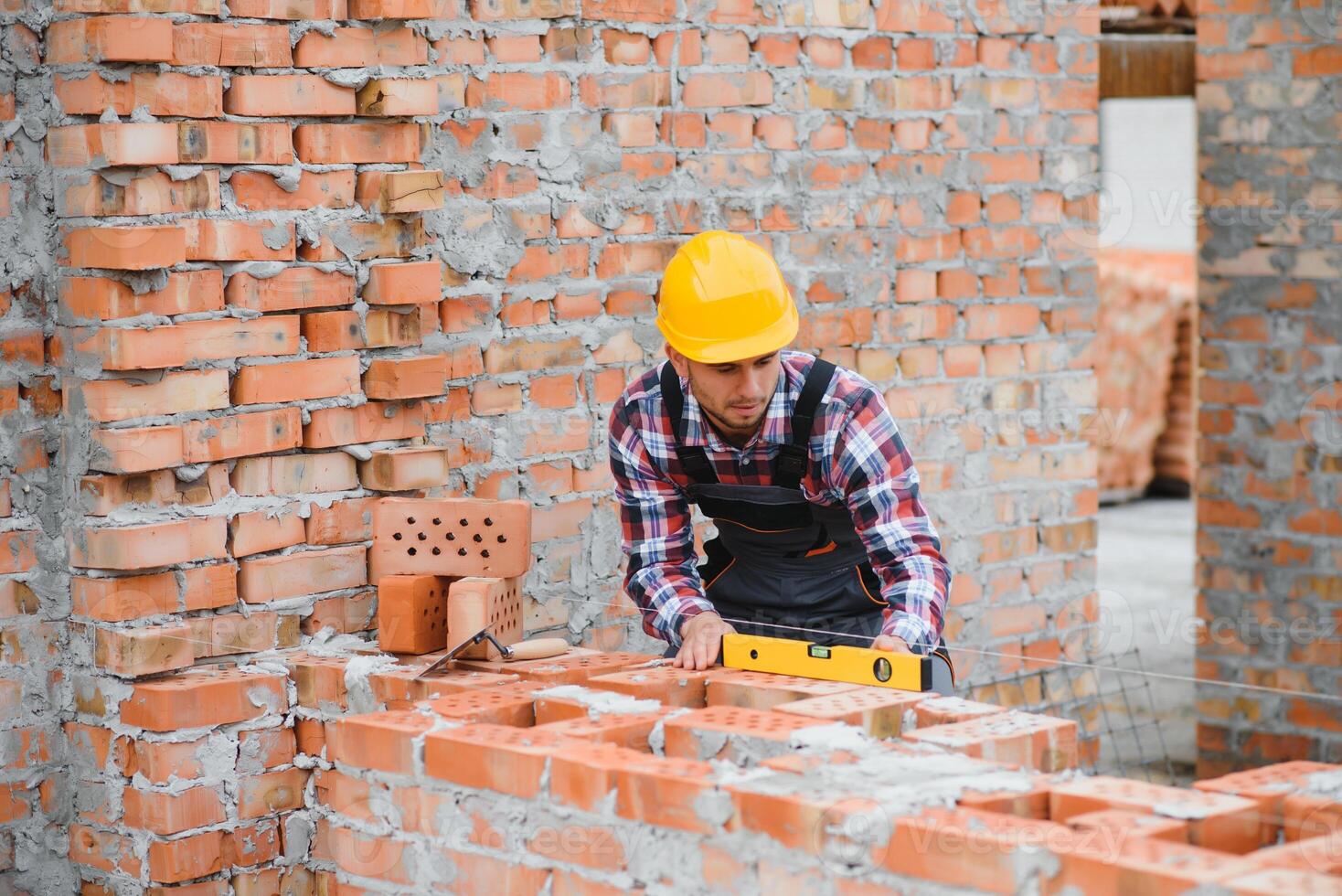 Yellow colored hard hat. Young man working in uniform at construction at daytime. photo