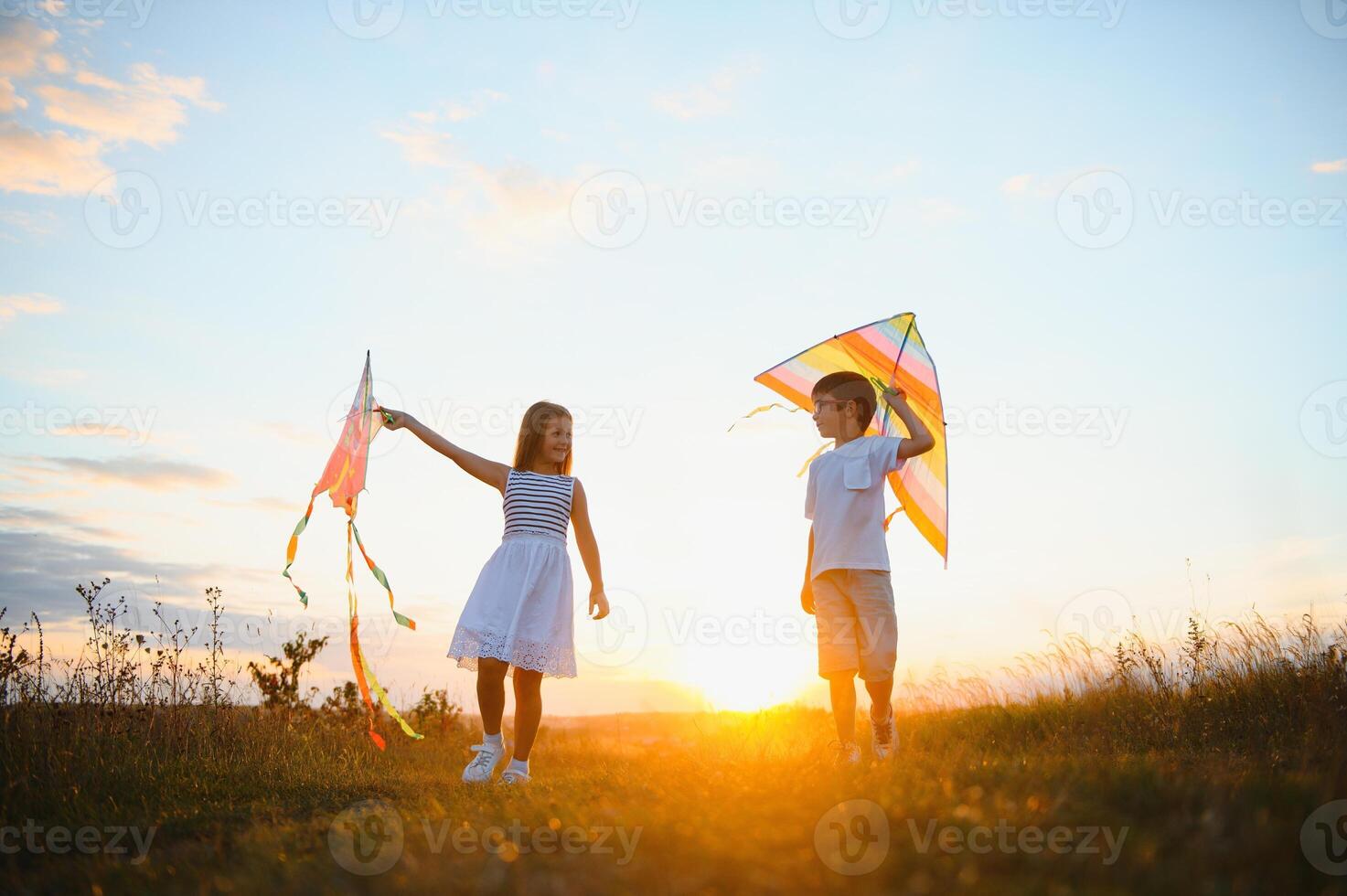 Happy children launch a kite in the field at sunset. Little boy and girl on summer vacation. photo