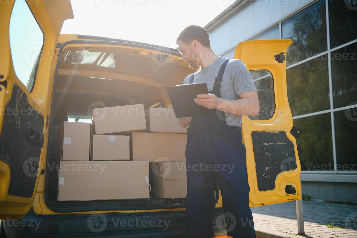 joven entrega hombre mensajero en uniforme sostener documentos portapapeles comprobación lista paquete o empaquetar enviar cajas cerca un coche para Servicio envío a cliente, en línea compras Servicio conceptos. foto