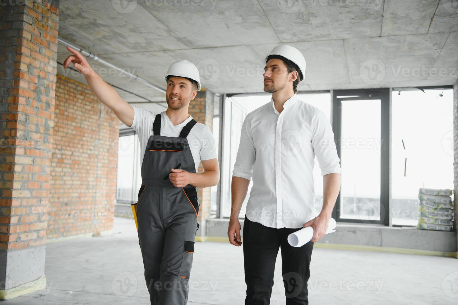 Engineer and worker checking project at building site background, construction site at sunset in evening time photo