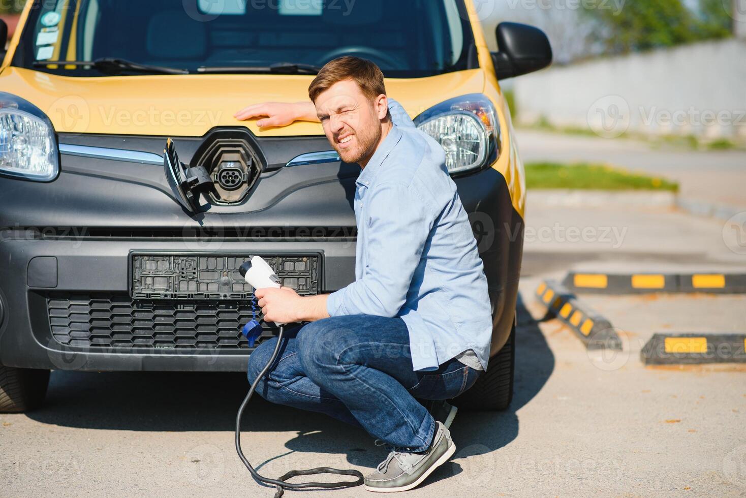 Smiling man unplugging the charger from the car photo