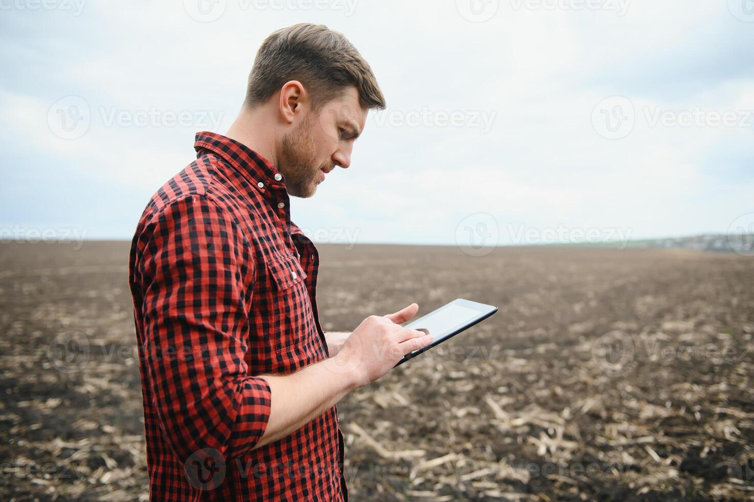 Young farmer in a field controlled sowing corn photo