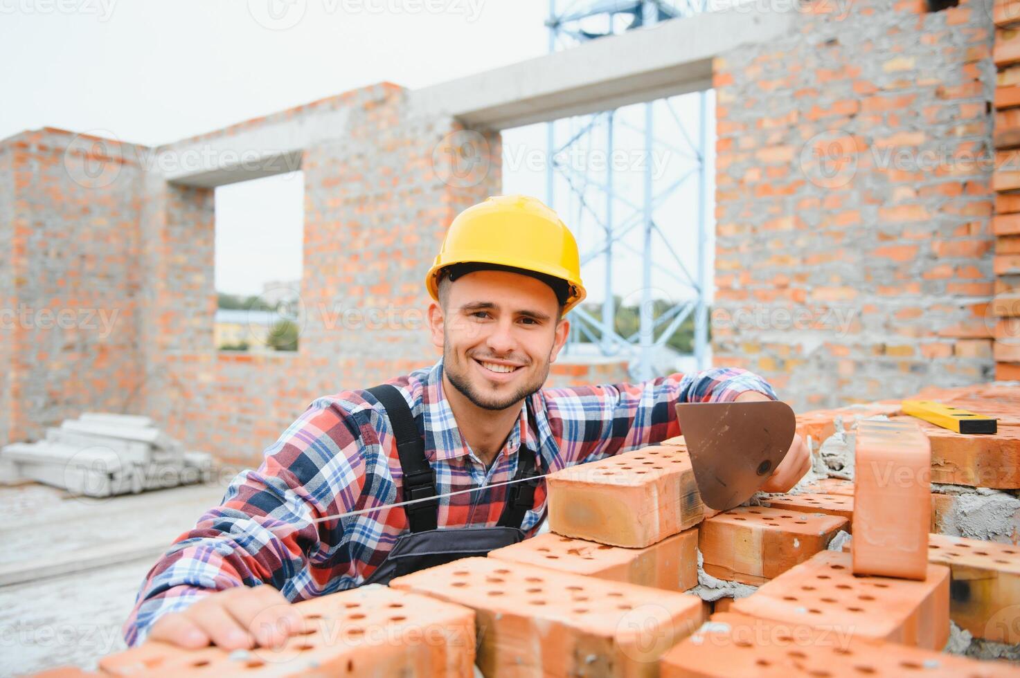Construction worker man in work clothes and a construction helmet. Portrait of positive male builder in hardhat working at construction site. photo