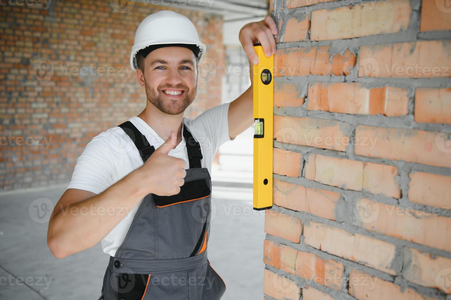 Portrait of handsome male builder in overalls and hard hat photo