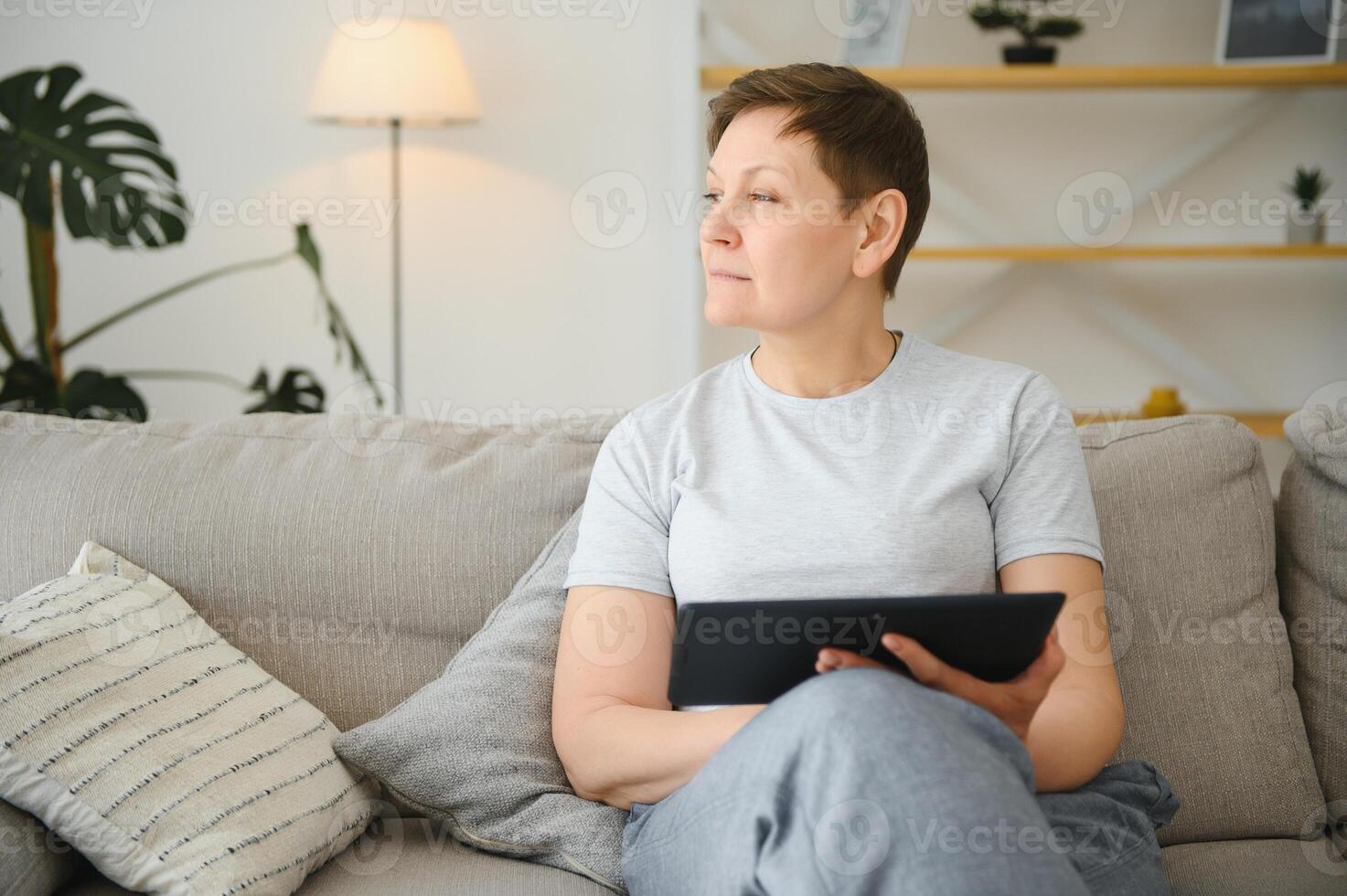 people, technology and internet concept - happy middle aged woman with tablet pc computer at home. photo