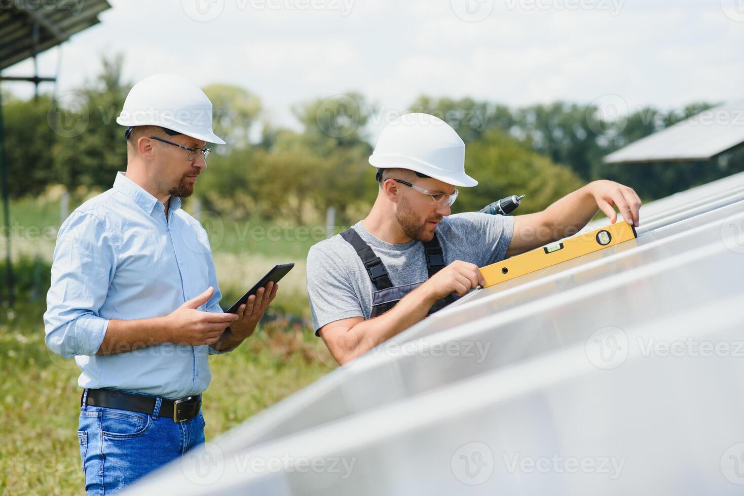 Male engineer in protective helmet installing solar photovoltaic panel system. Alternative energy ecological concept. photo