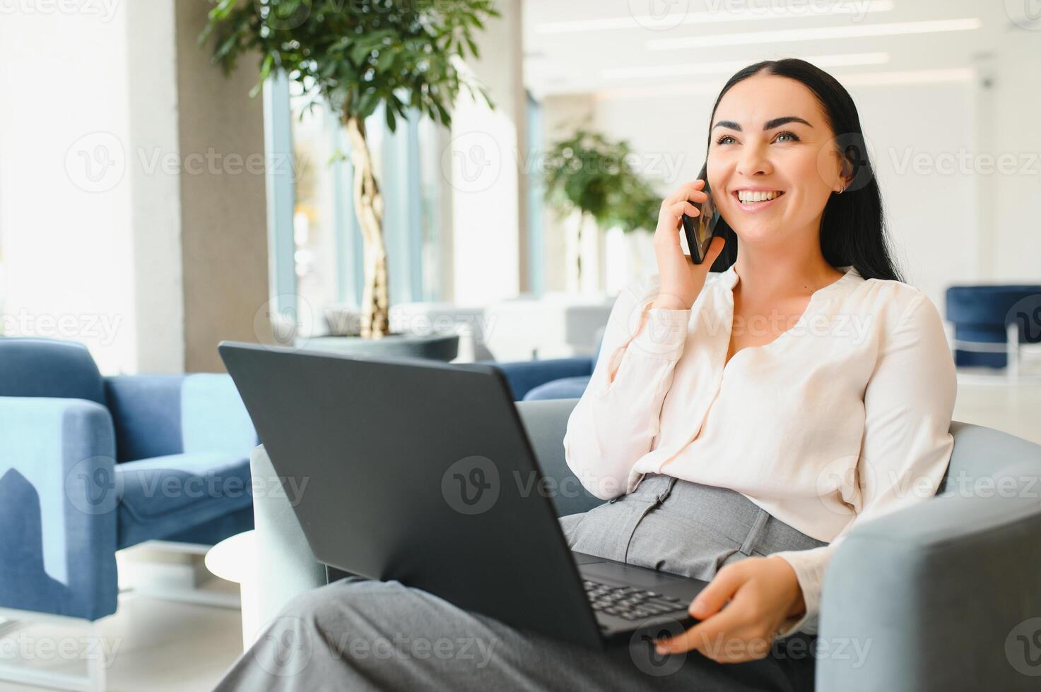 Young beautiful woman sitting at a shopping center and working at a computer laptop, using mobile phone. Freelance and business concept. photo