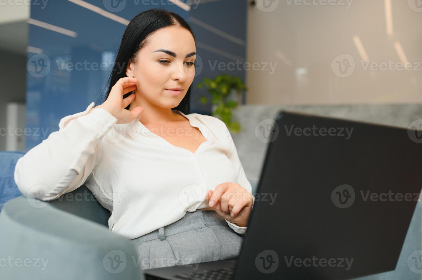 Young beautiful woman sitting at a shopping center and working at a computer laptop, using mobile phone. Freelance and business concept. photo