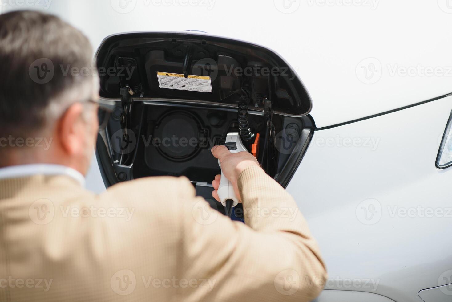 Man charges an electric car at the charging station photo