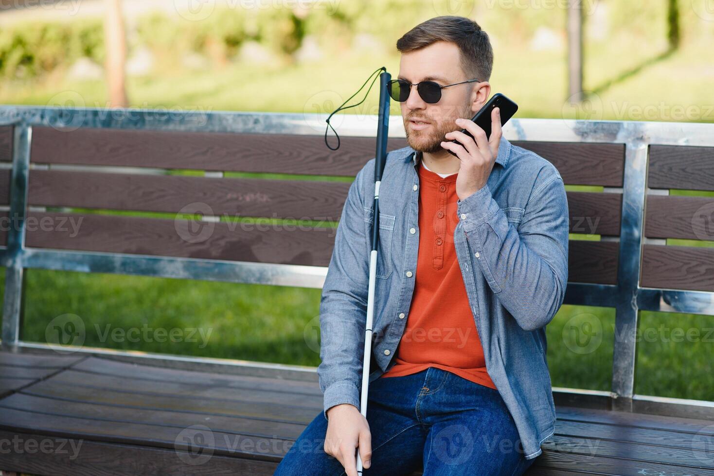 Young blinded man using phone and sending voice message photo