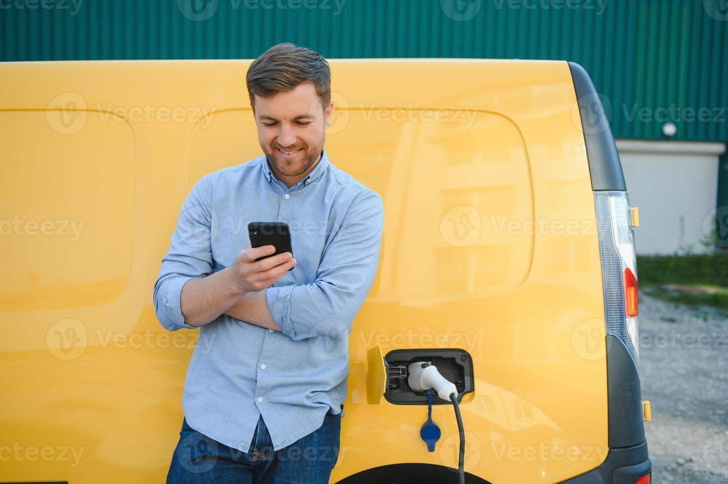 Handsome man using phone while car being charged photo