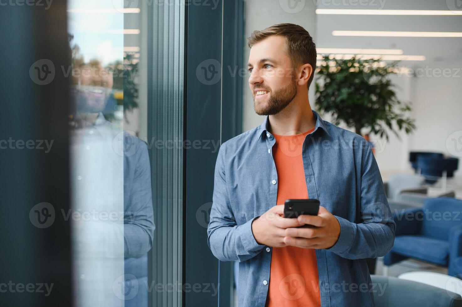 Image of handsome serious young man talking cellphone while working at office. photo