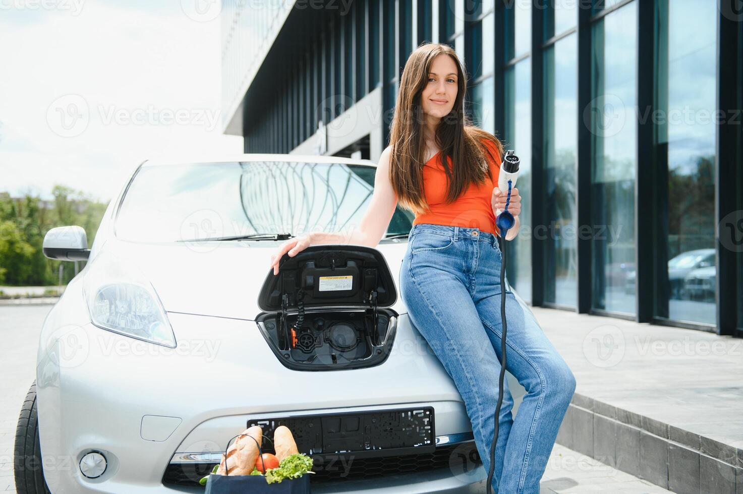 mujer cargando electro coche a el eléctrico gas estación foto