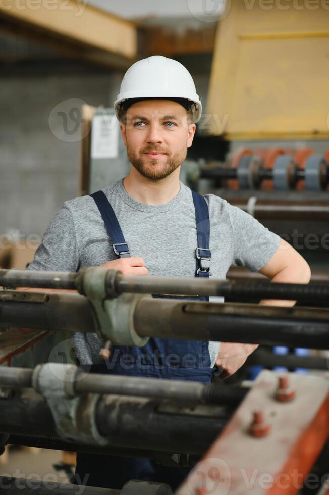 worker in protective clothing in factory using machine photo