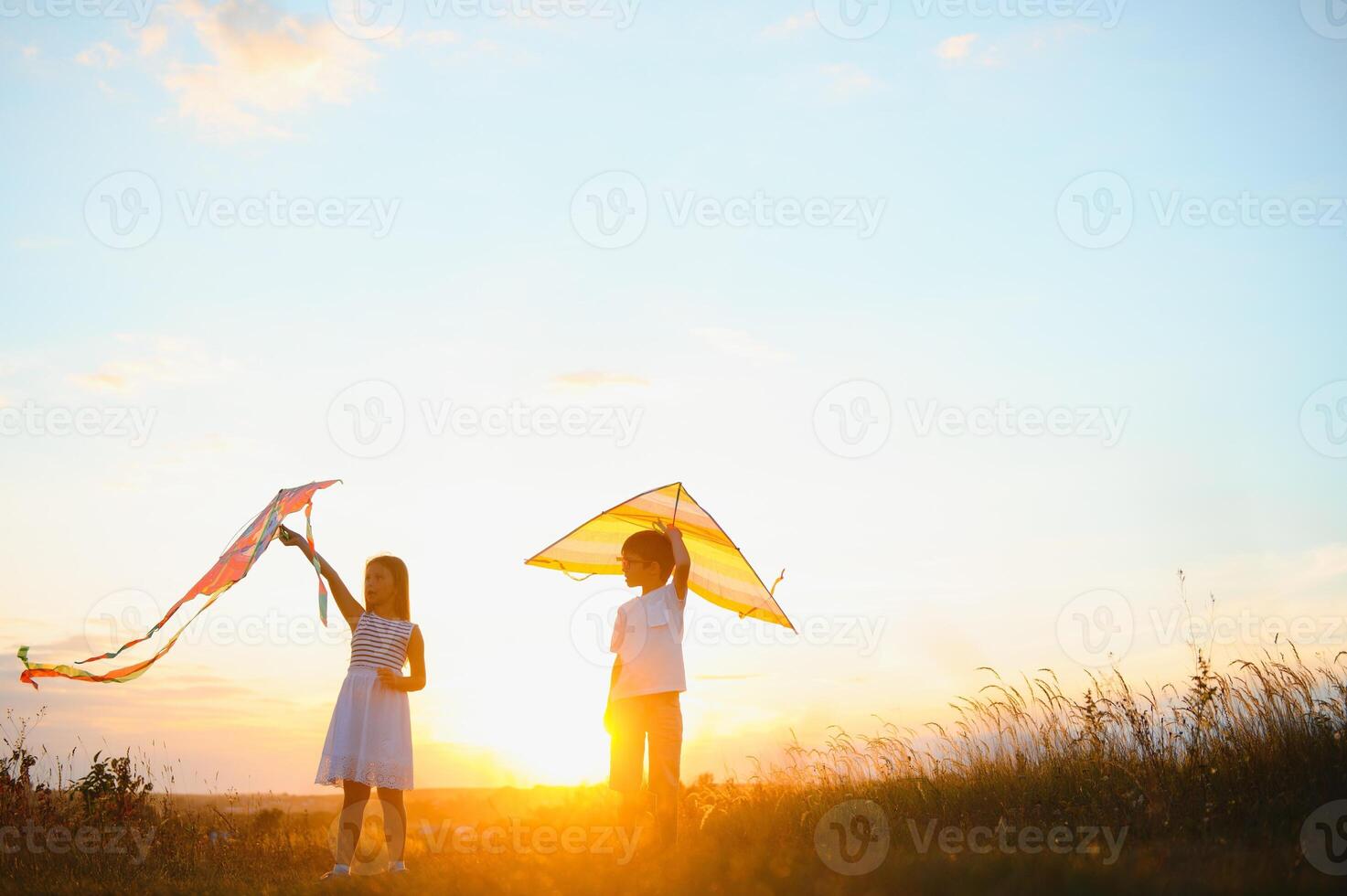 Children launch a kite in the field at sunset photo