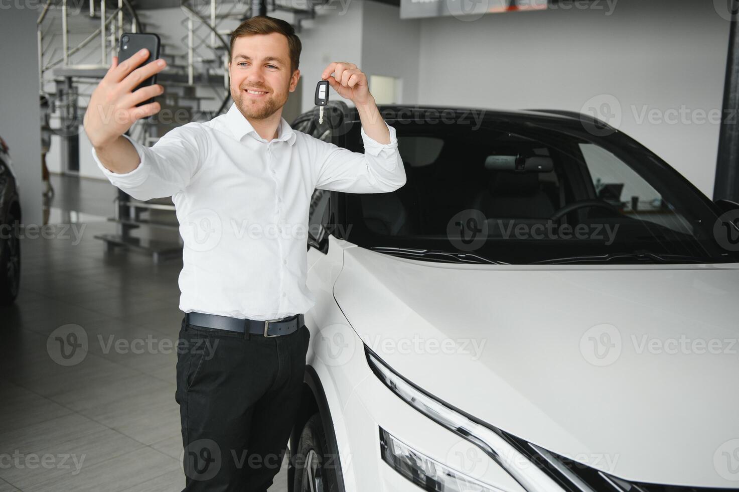 Yes, that's my new car. Customer in car dealership. Young man with keys in hand. photo