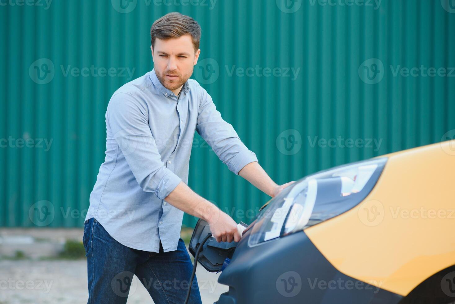 Smiling man unplugging the charger from the car photo