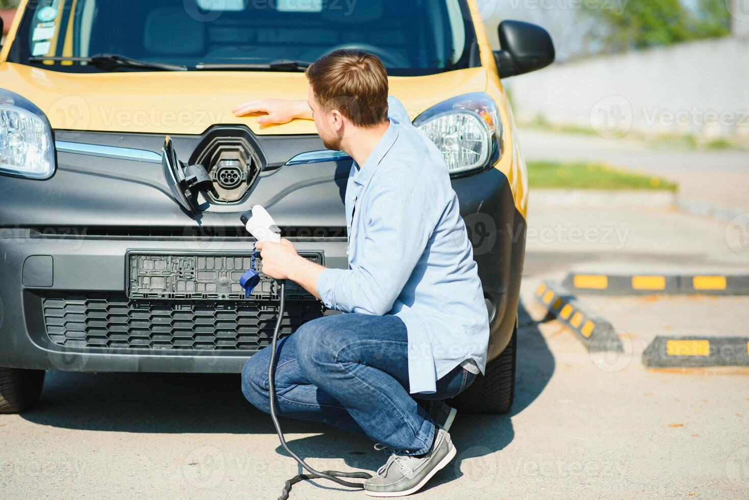 Smiling man unplugging the charger from the car photo