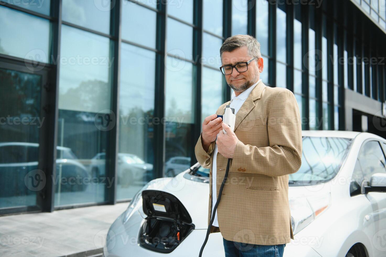 a businessman charges an electric car photo