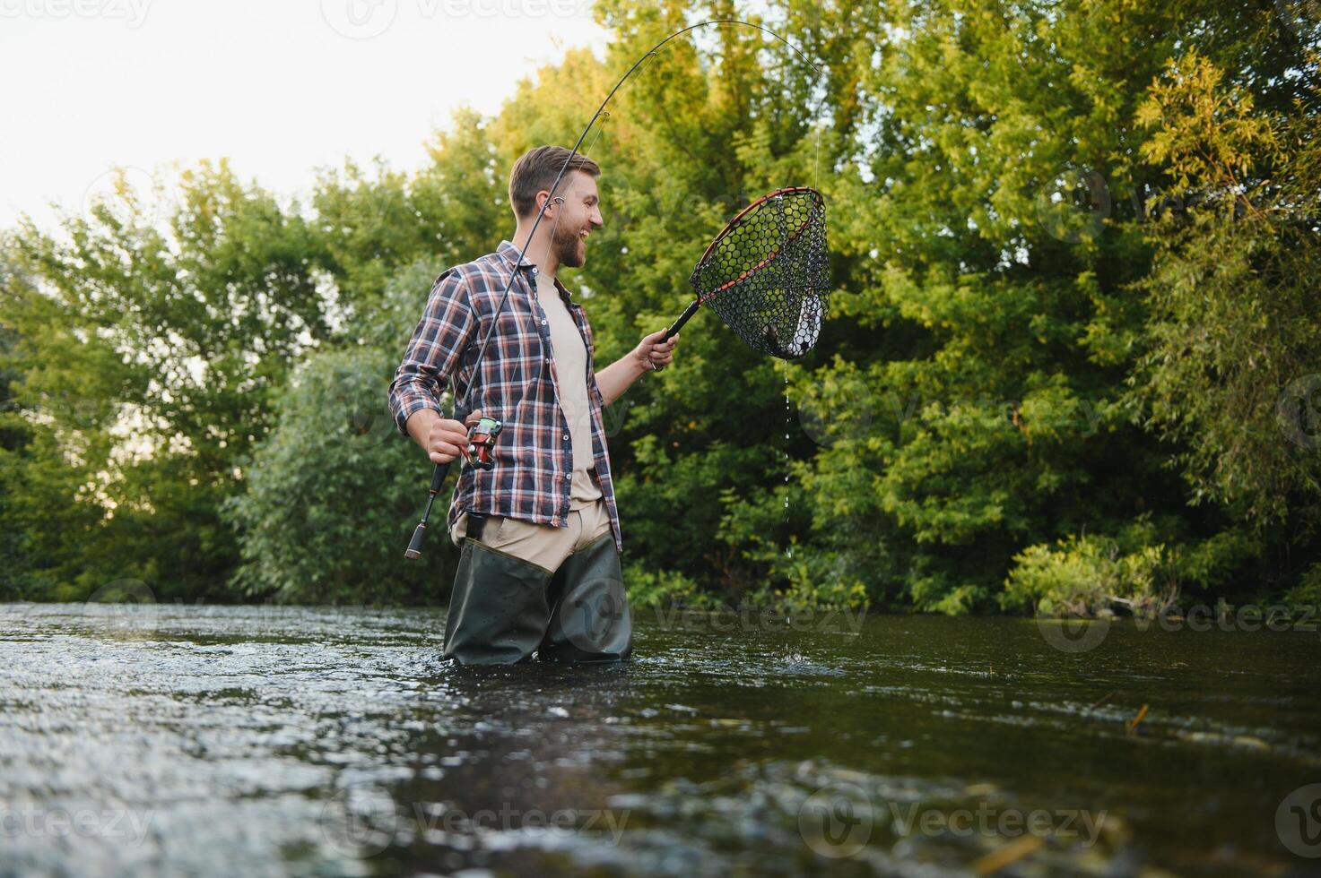 Fly-fisherman holding trout out of the water photo