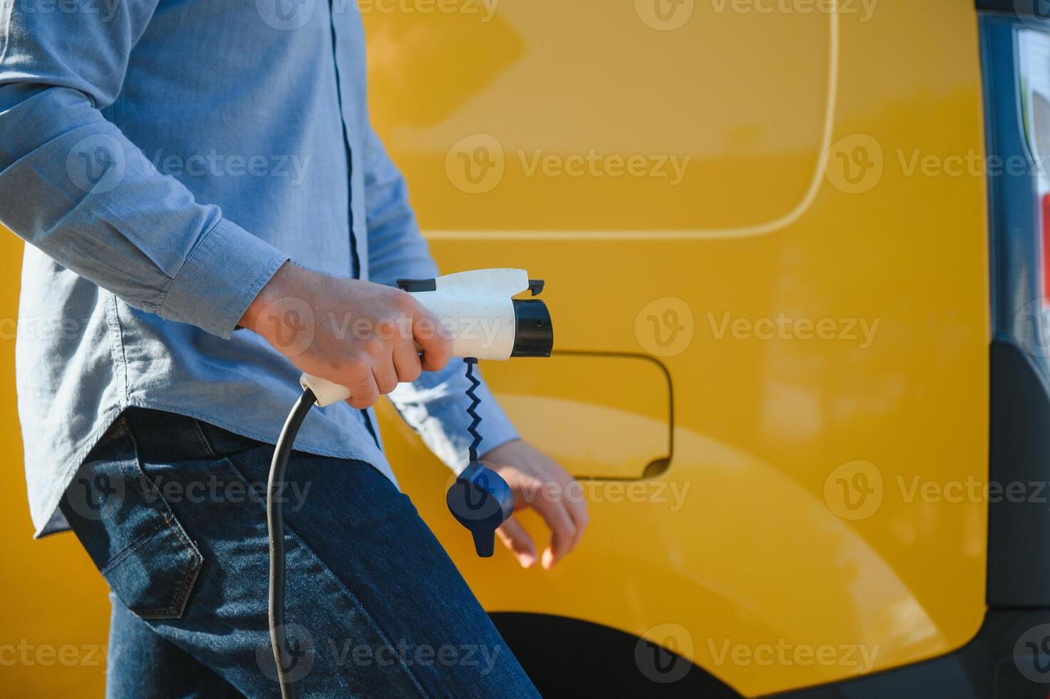 Smiling man unplugging the charger from the car photo