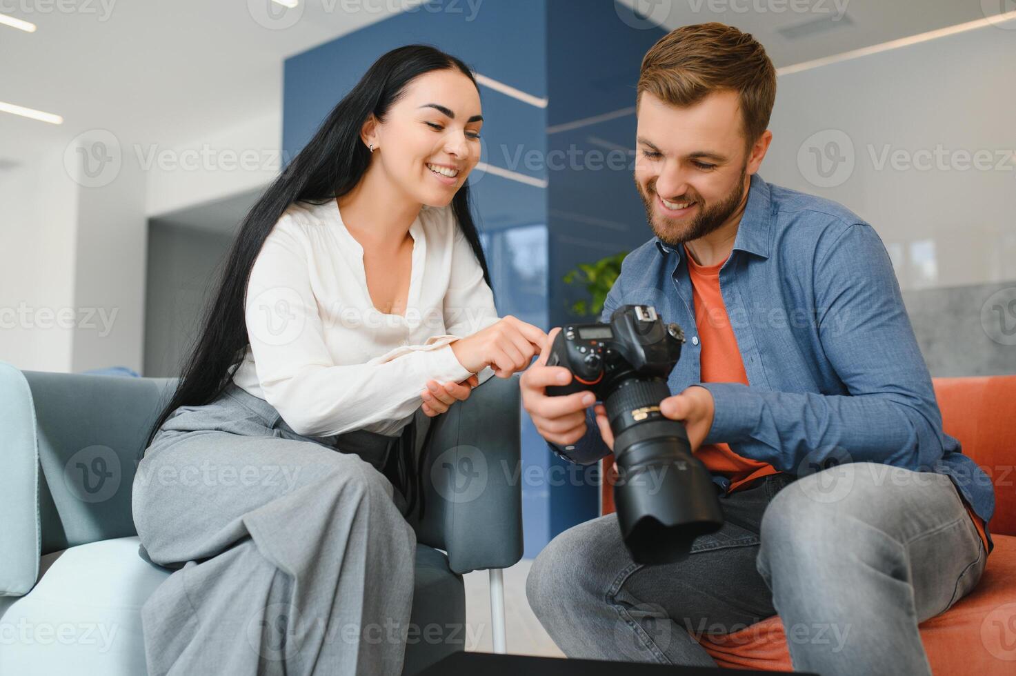 Photographer in office shows photo model in camera. Consultant adjusts activities company as whole. Photo session employees in workplace. Manager well-executed project. Photos best employees company.