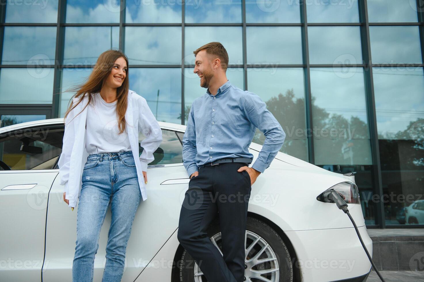 Pareja en el cargando estación para eléctrico vehículos foto