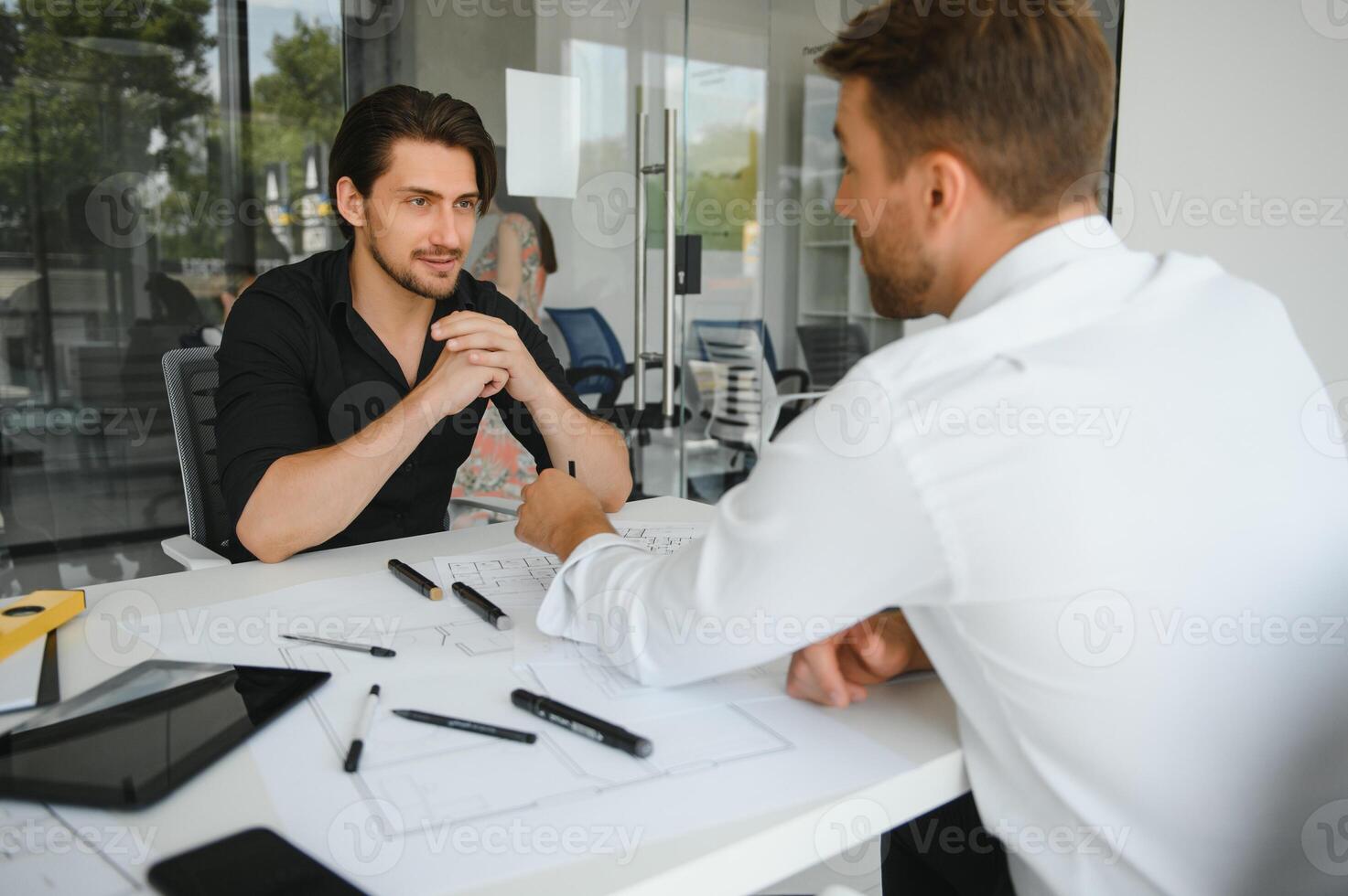 two people sit in front of construction plan and talk about the architecture photo