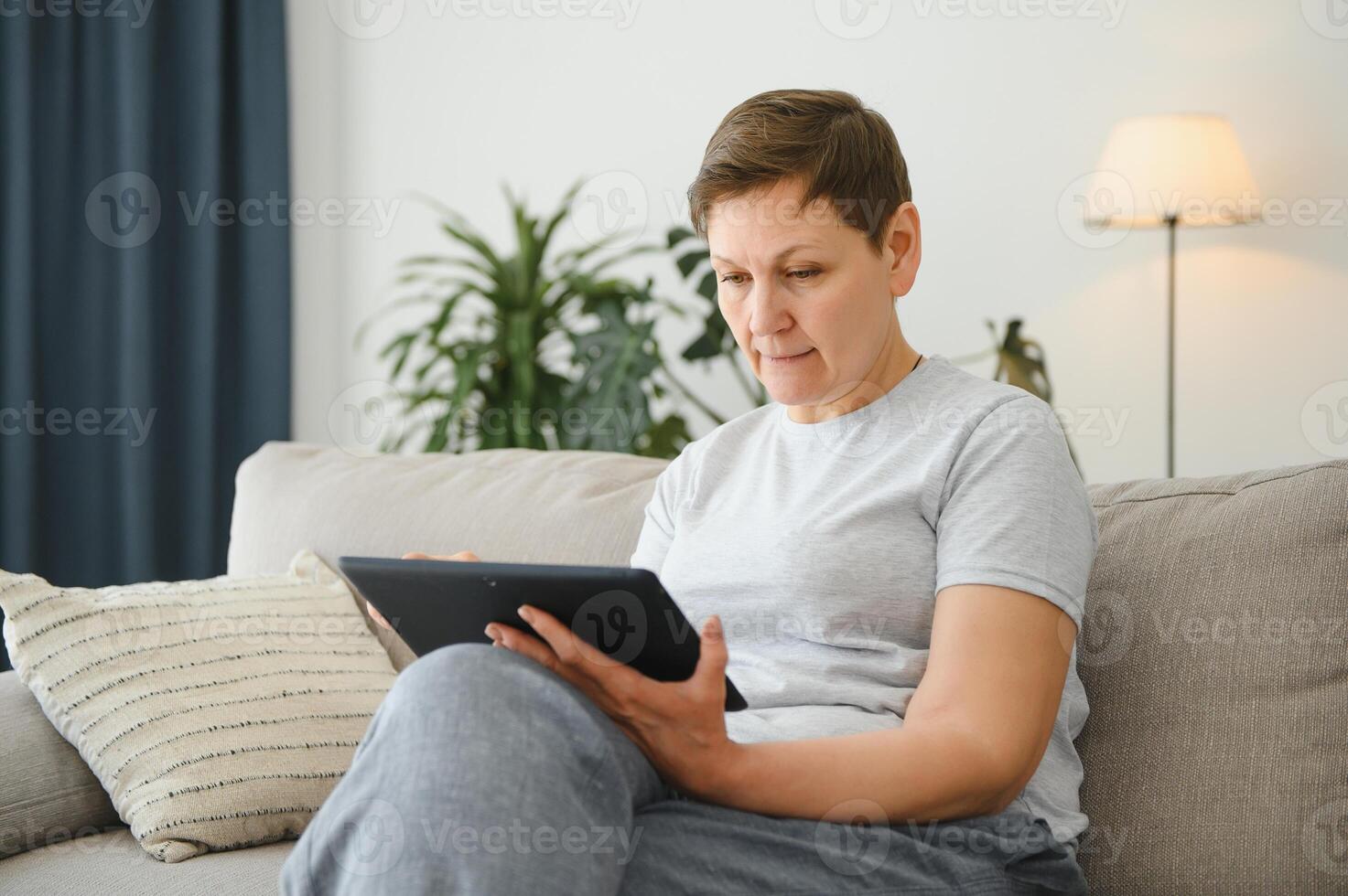 people, technology and internet concept - happy middle aged woman with tablet pc computer at home. photo