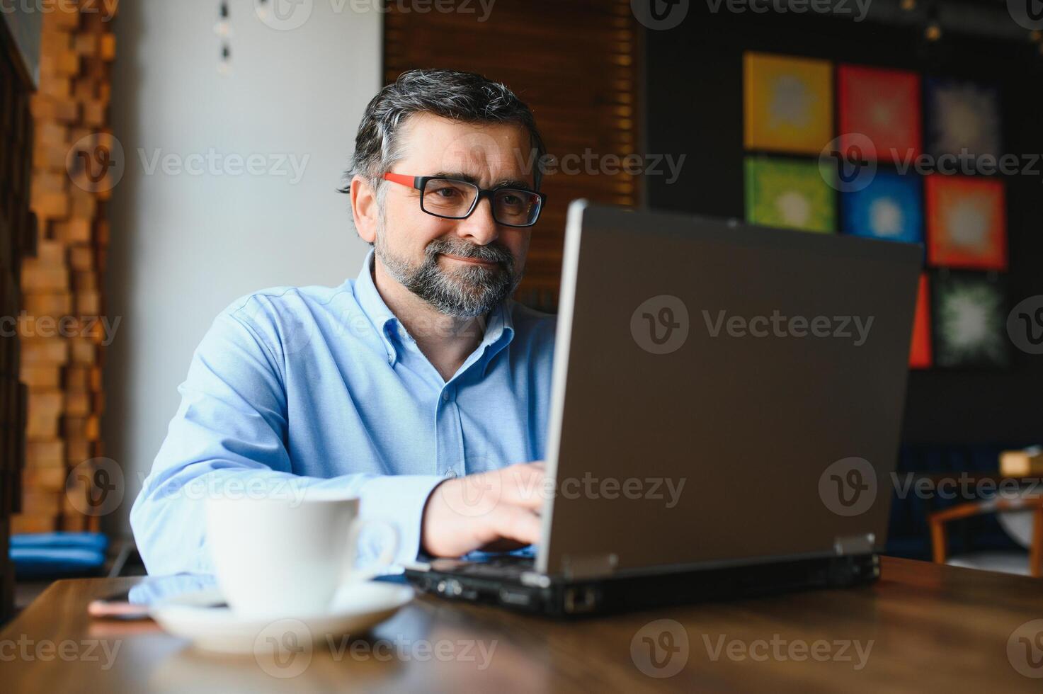 Business, technology and people concept , senior businessman with laptop computer drinking coffee at modern cafe. photo