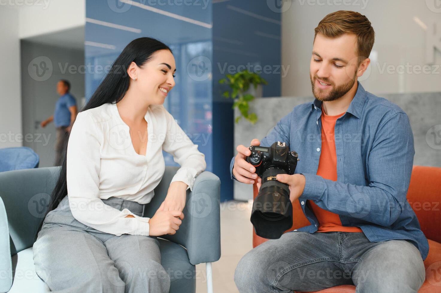 Photographer in office shows photo model in camera. Consultant adjusts activities company as whole. Photo session employees in workplace. Manager well-executed project. Photos best employees company.