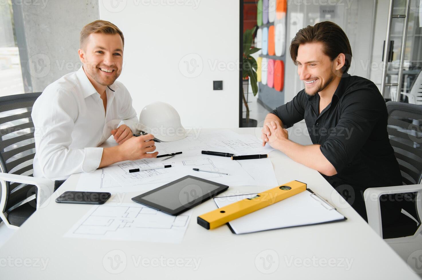 two people sit in front of construction plan and talk about the architecture photo