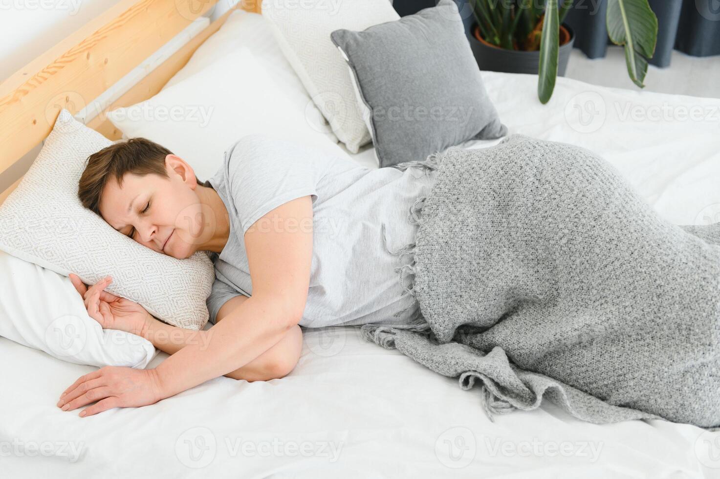 mujer dormido en cama debajo blanco edredón con cabeza en almohada foto