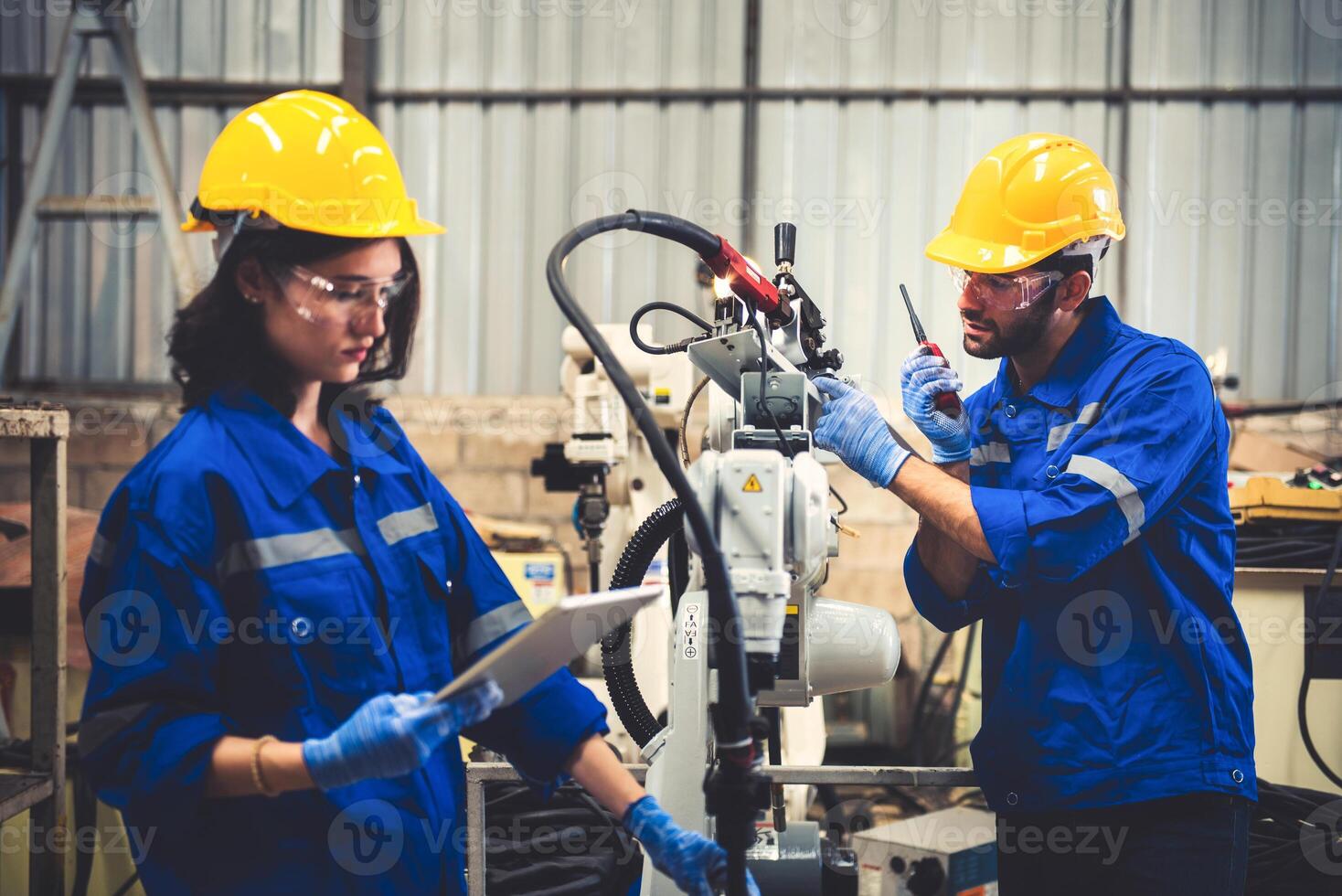 Two engineers mechanic using computer controller Robotic arm for welding steel in steel factory workshop. Industry robot programming software for automated manufacturing technology photo