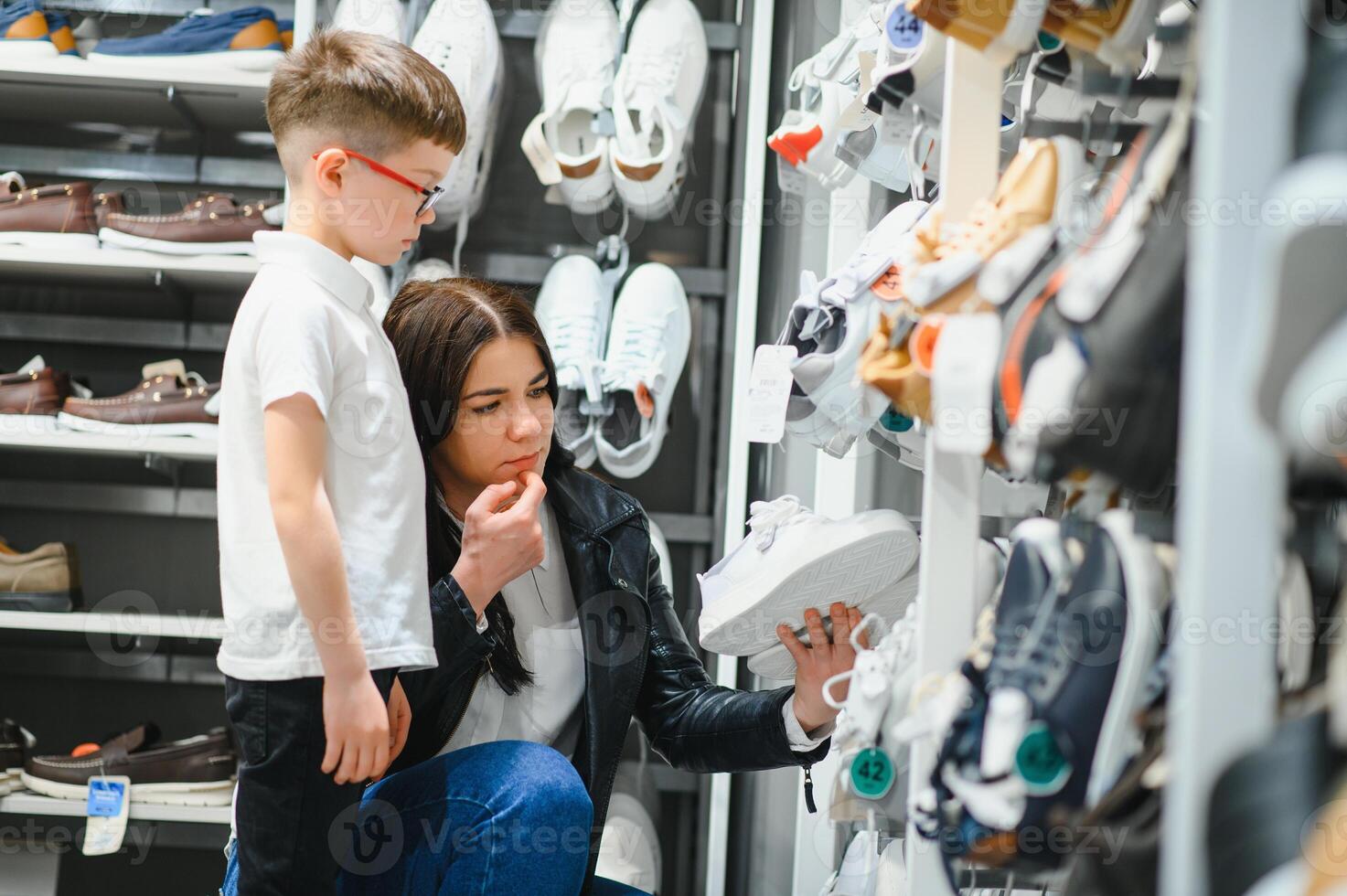 Mother with children choosing shoes in kids store photo