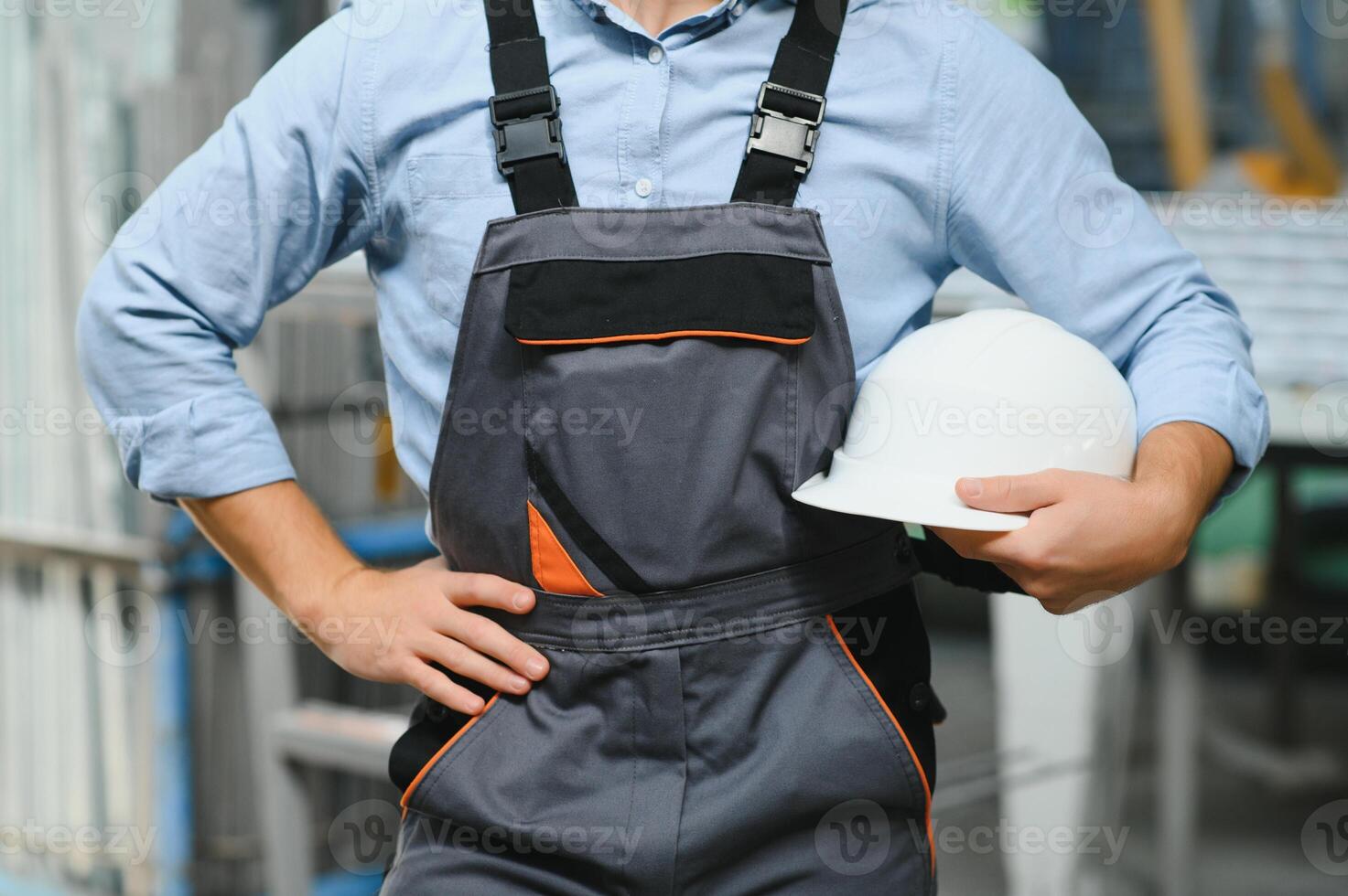 Portrait of factory worker in protective uniform and hardhat standing by industrial machine at production line. People working in industry photo