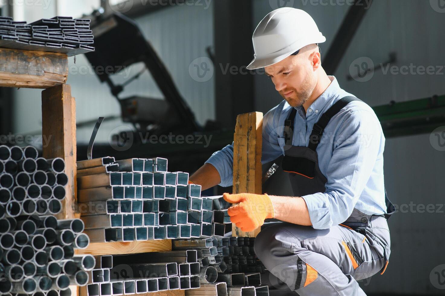 Portrait of factory worker in protective uniform and hardhat standing by industrial machine at production line. People working in industry photo