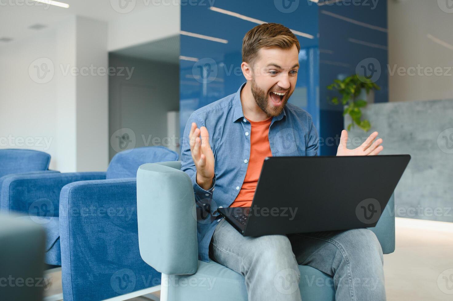 Photo of young excited man happy positive smile celebrate win victory success fists hands sit sofa home remote work.