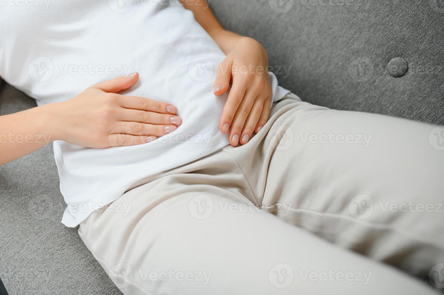 joven mujer sufrimiento desde abdominal dolor a hogar. ginecología concepto foto