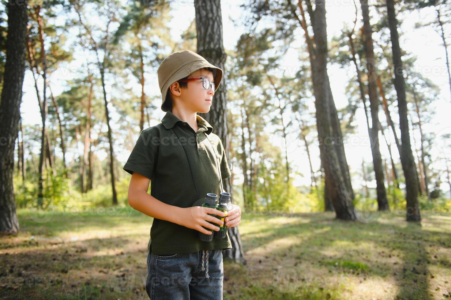 Little boy scout with binoculars during hiking in autumn forest. Concepts of adventure, scouting and hiking tourism for kids. photo