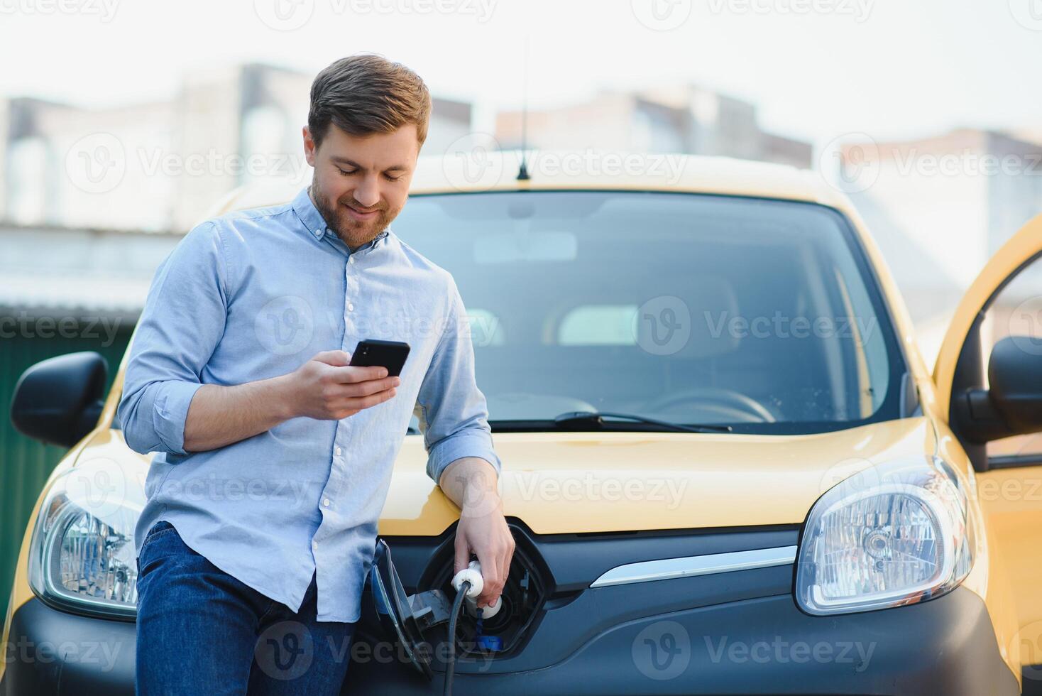 Smiling man unplugging the charger from the car photo