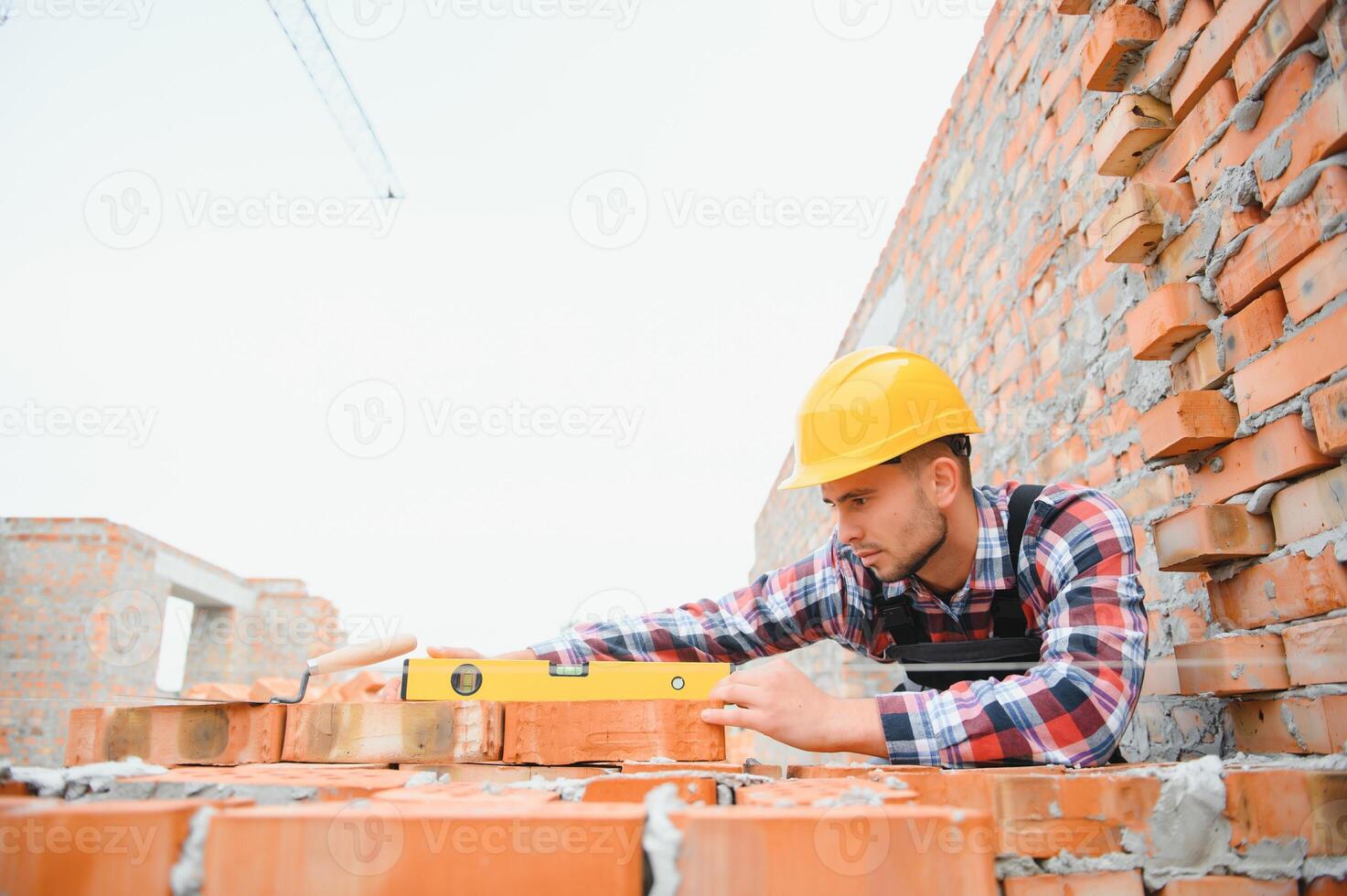 instalación de pared de ladrillo. trabajador de la construcción en uniforme y equipo de seguridad tiene trabajo en la construcción foto