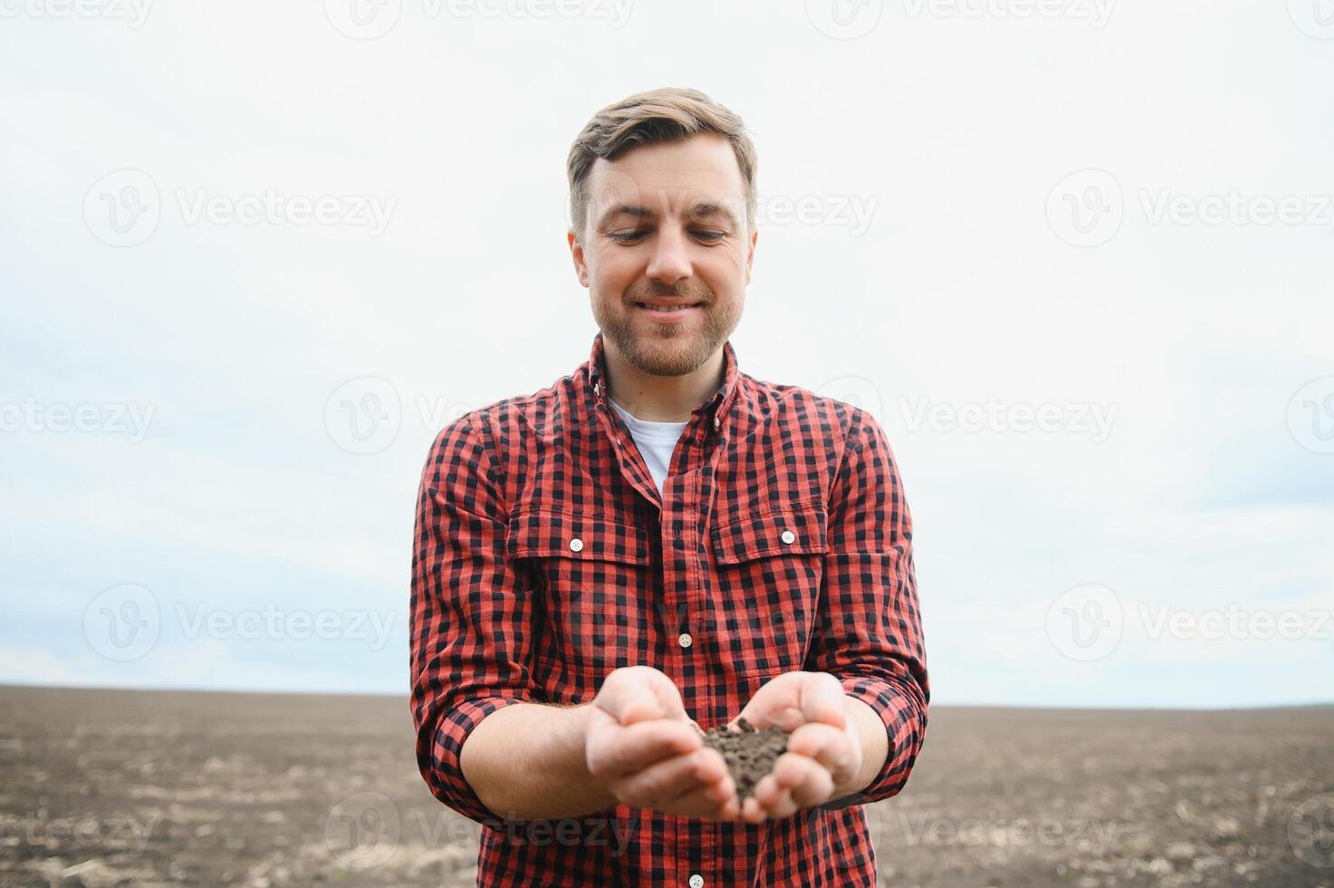 A farmer in boots works with his tablet in a field sown in spring. An agronomist walks the earth, assessing a plowed field in autumn. Agriculture. Smart farming technologies photo