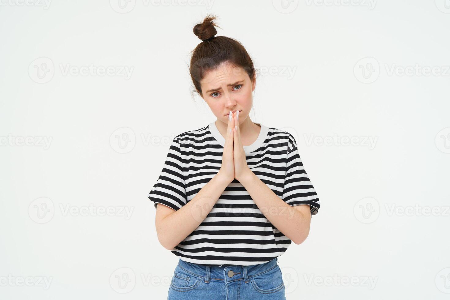 Please. Young woman asks for help, begs you, holds hands in pray, pleading, isolated against white background photo