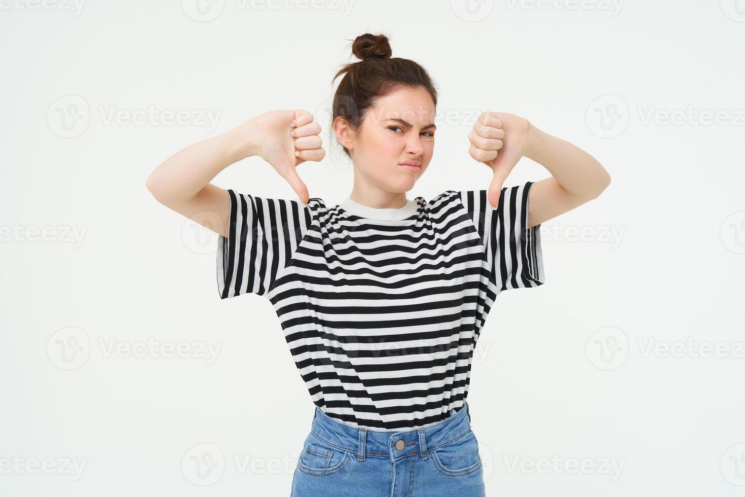 retrato de decepcionado, joven moderno mujer, estudiante muestra pulgares abajo, no le gusta algo, desaprueba, soportes terminado blanco antecedentes foto