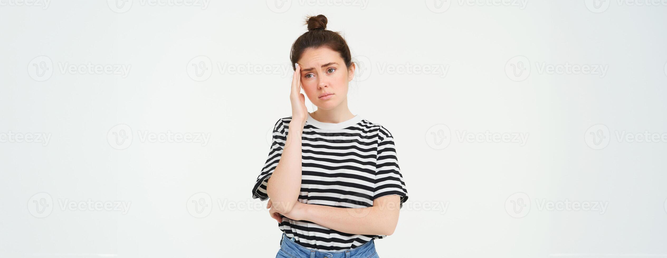 Portrait of concerned, worried young woman, touches her head, looking complicated, standing over white background photo