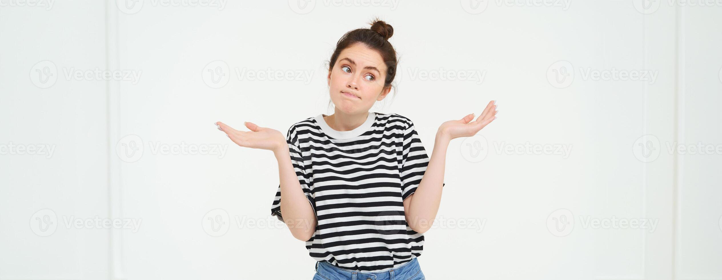 Image of confused brunette girl shrugging shoulders, looks puzzled, isolated over white background photo